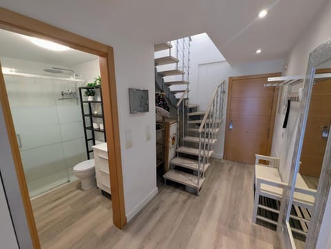 Hall with the downstairs bathroom, stairs to the upper floor and the entrance door