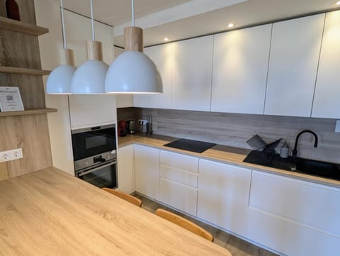 Modern white kitchen with induction hob, oven and pendant lights