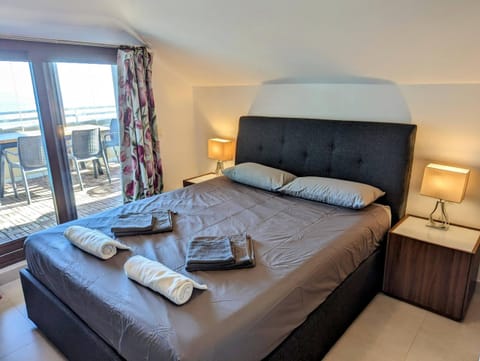Bedroom with double bed and a glass door onto the terrace with sea view