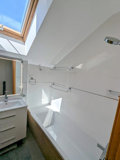 Upstairs bathroom with bathtub under a sloping ceiling and skylight